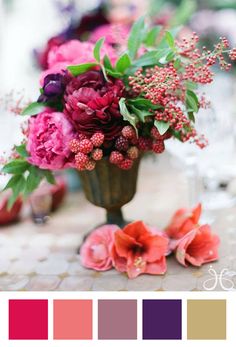 a vase filled with lots of pink and red flowers sitting on top of a table