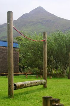 a wooden bench sitting in the middle of a lush green field next to a tall mountain