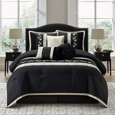 a black and white bed in a bedroom next to two nightstands with lamps on them