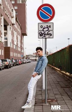 a young man leaning against a street sign