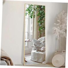 a large mirror sitting in the middle of a room next to a chair and potted plant