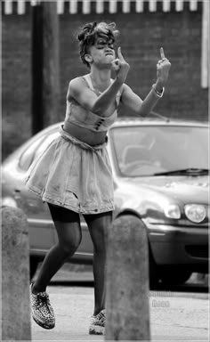 a woman standing on the sidewalk making a peace sign