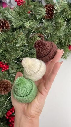 two knitted hats sitting on top of each other in front of a christmas tree