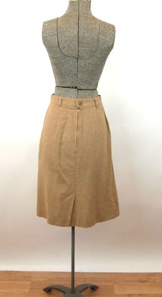 "This 1970s skirt is a nice, classic piece that can go with anything. It's made of tan wool, in an A-line style, with zipper and button in back. Unlined. Made by JRS. Good condition. Measurements - Waist - 24\" Hip - 36\" Length - 23\" * Proud member of the Vintage Fashion Guild * For more vintage fashions, visit Vintage Runways' shop at http://www.vintagerunway.etsy.com. Follow on Instagram - instagram.com/vtgrunway Follow on Tumblr - vintagerunwayetsy.tumblr.com" Classic Brown Wool Skirt, Vintage Brown Skirt For Workwear, Vintage Brown Skirt For Work, Vintage Wool Lined Skirt, Vintage Brown Wool Skirt, Fitted Wool Skirt With Pockets, Brown Vintage Wool Skirt, Fitted Wool Skirt In Brown, Fitted Brown Wool Skirt