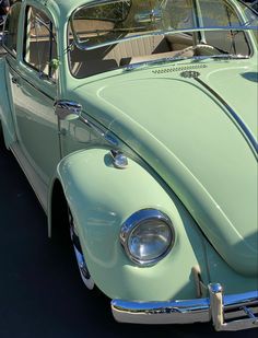 an old green car parked in a parking lot