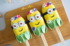 three cake pops decorated to look like minion's with flowers and leaves on them