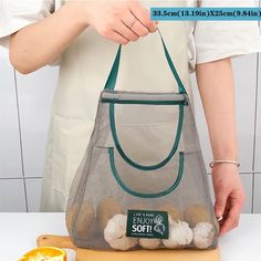 a person holding a mesh bag filled with eggs and an orange on a cutting board