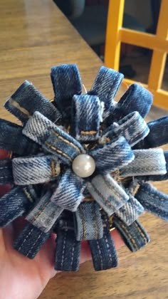 someone is holding up a denim flower with pearls on the center, and it looks like they are made out of old jeans