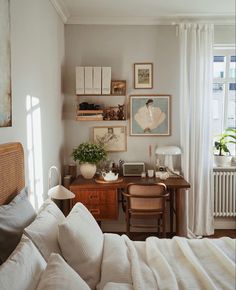 a bed sitting under a window next to a desk with a lamp on top of it