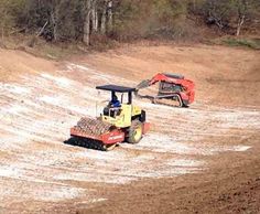 two tractors are parked in the middle of a dirt field