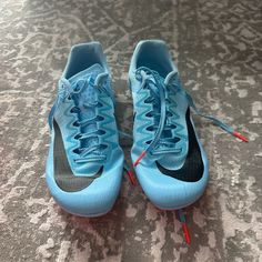 a pair of blue and black nike shoes with red string attached to them on a carpeted floor