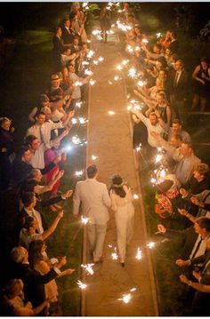 the bride and groom are walking down the aisle with their sparklers