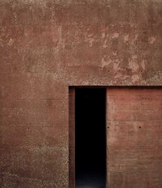 an open door on the side of a building with no people in it and only one person standing outside