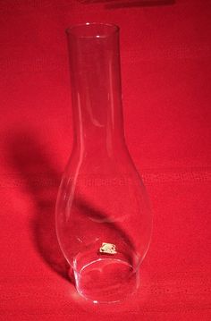 a glass vase with a tiny gold object in it on a red tableclothed surface