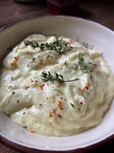 a white bowl filled with mashed potatoes and garnished with herbs