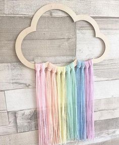 an image of a rainbow cloud with fringes hanging from it's side on a wooden wall