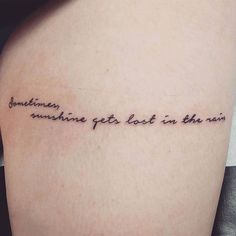 someone got this in the rain tattoo on her left thigh and it says sometimes sunshine get lost in the rain