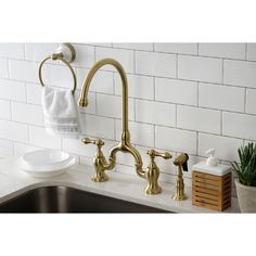 a kitchen sink with gold faucet and soap dispenser next to it