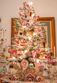 a white christmas tree decorated with candy canes and candies in the shape of houses