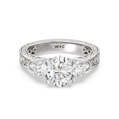 a three stone engagement ring with diamonds on the band and side stones in white gold