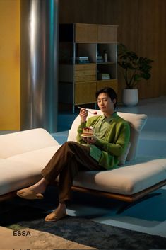 a man sitting on a couch holding a cup