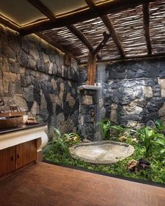 an outdoor shower in the middle of a stone wall and wood flooring, surrounded by greenery