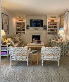 a living room filled with furniture and a flat screen tv mounted on the wall above a fire place