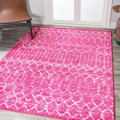 a bright pink area rug in front of a door with a chair and vase on the floor