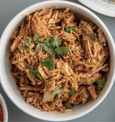 a white bowl filled with shredded chicken and cilantro