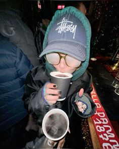 a person wearing a hat and glasses drinking from a cup