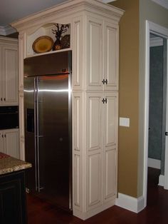 a kitchen with white cabinets and stainless steel refrigerator