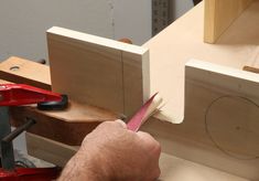 a man is using a pair of scissors to cut the edge of a piece of wood