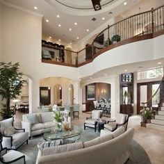 a living room filled with lots of furniture and a spiral staircase leading up to the second floor