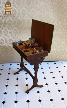 a small wooden table with an open drawer on it's top and several other items in the tray