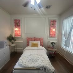 a white bed sitting in a bedroom next to two windows