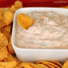 a white bowl filled with dip surrounded by tortilla chips