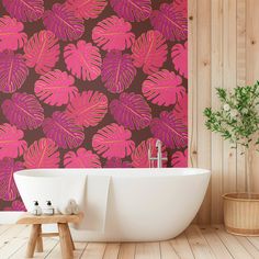 a bath tub sitting next to a wall with pink and brown leaves on the wall