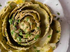 an artichoke on a plate with lemon wedges and parsley garnish