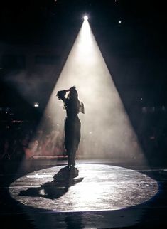 a woman standing on top of a stage under a spotlight