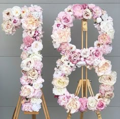 the letter o is made out of pink and white flowers on a wooden easel