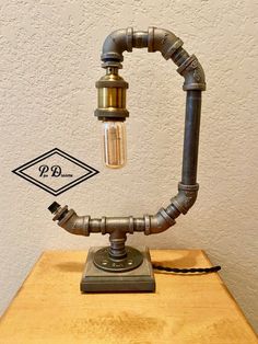 an old fashioned lamp made out of pipes on top of a wooden table