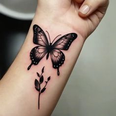 a black and white butterfly tattoo on the wrist