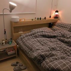 an unmade bed sitting next to a night stand with two lamps on top of it