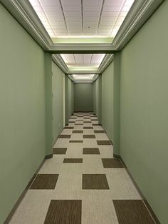 an empty hallway with green walls and checkered flooring