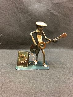 a bronze figurine is holding a guitar