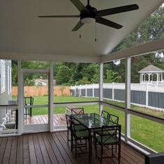 a screened porch with table, chairs and ceiling fan on the back deck overlooking an enclosed yard