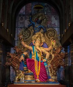 a statue of the hindu god ganesh in front of a stained glass window