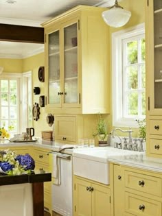 a kitchen filled with lots of yellow cabinets and white counter top space next to a window