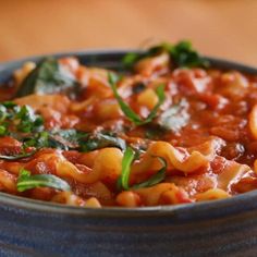 a blue bowl filled with pasta and spinach