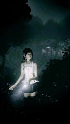 a girl standing in the dark holding a flashlight